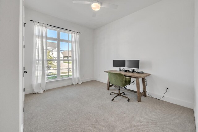 home office with light carpet, ceiling fan, and a healthy amount of sunlight