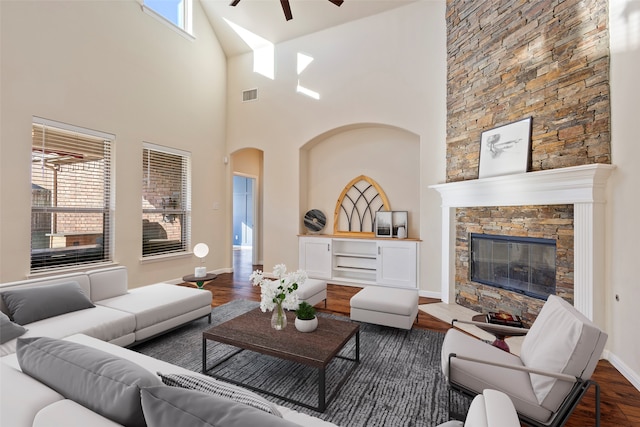 living room featuring a fireplace, high vaulted ceiling, a wealth of natural light, and dark wood-type flooring