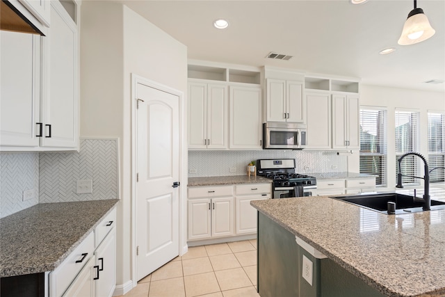 kitchen featuring light stone countertops, white cabinetry, sink, stainless steel appliances, and decorative light fixtures