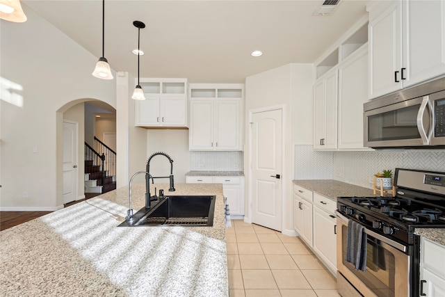 kitchen with light stone countertops, sink, stainless steel appliances, pendant lighting, and white cabinets