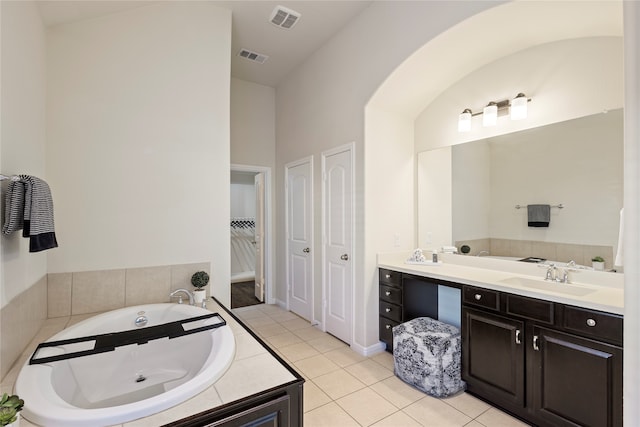 bathroom featuring tiled bath, tile patterned flooring, and vanity