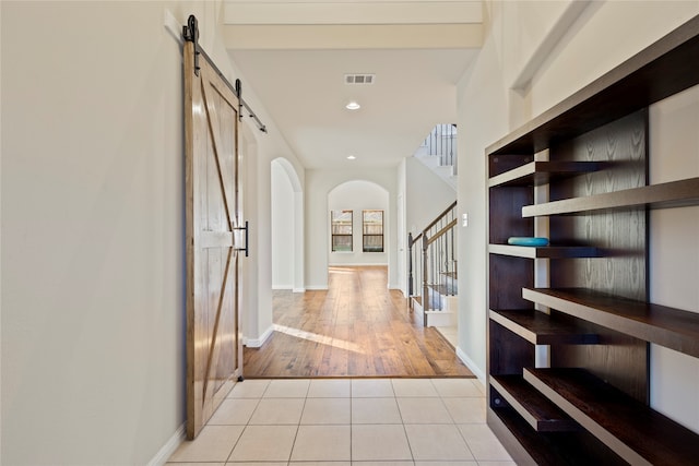 hallway featuring light wood-type flooring and a barn door