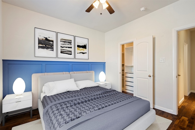 bedroom with ceiling fan, dark hardwood / wood-style floors, a spacious closet, and a closet