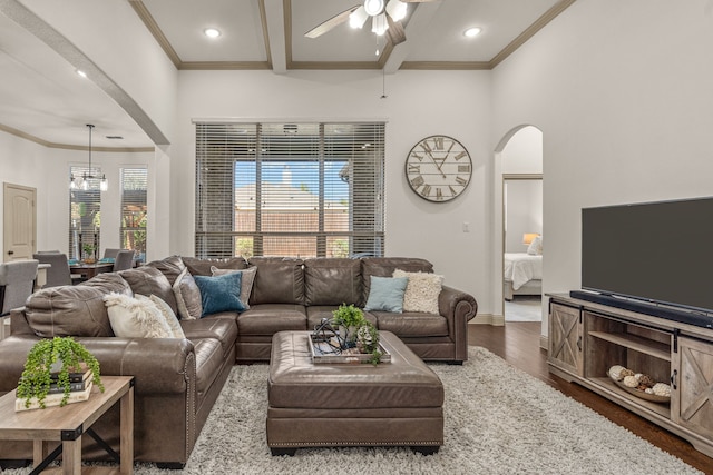 living room with beamed ceiling, ceiling fan with notable chandelier, crown molding, and dark wood-type flooring