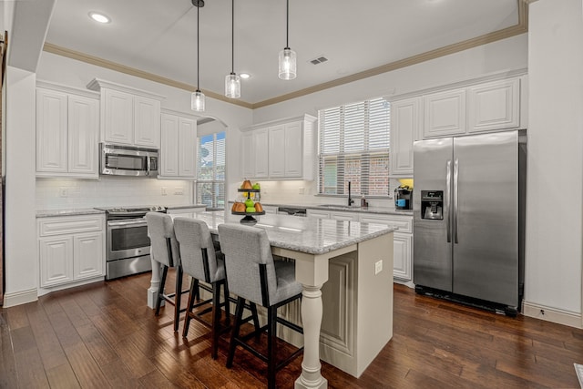 kitchen featuring a healthy amount of sunlight, a kitchen island, stainless steel appliances, and dark hardwood / wood-style floors