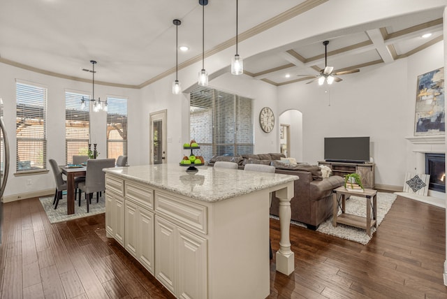 kitchen with coffered ceiling, light stone counters, a center island, and dark hardwood / wood-style floors