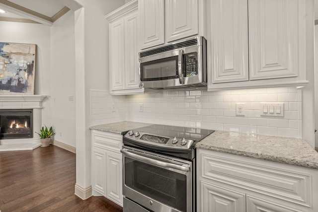 kitchen with light stone countertops, dark hardwood / wood-style floors, crown molding, white cabinets, and appliances with stainless steel finishes