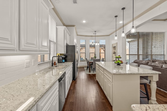 kitchen featuring light stone countertops, dark wood-type flooring, sink, white cabinetry, and hanging light fixtures