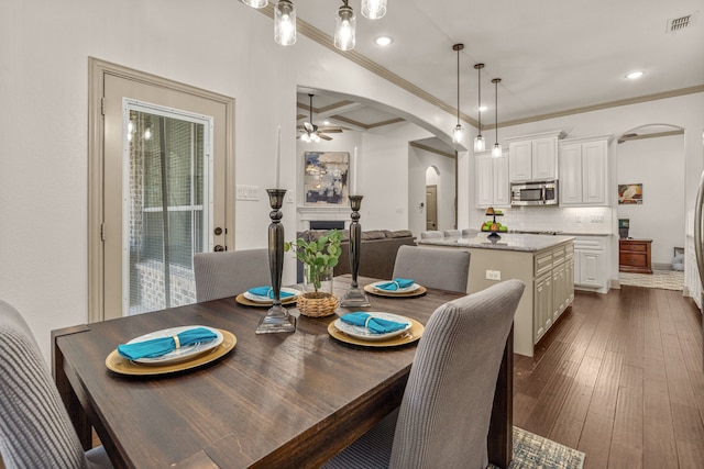 dining room featuring coffered ceiling, dark hardwood / wood-style floors, ceiling fan, ornamental molding, and beam ceiling