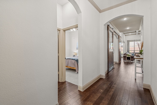 corridor featuring dark hardwood / wood-style floors, a barn door, and ornamental molding