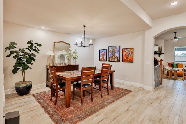 dining room with light hardwood / wood-style flooring and ceiling fan with notable chandelier