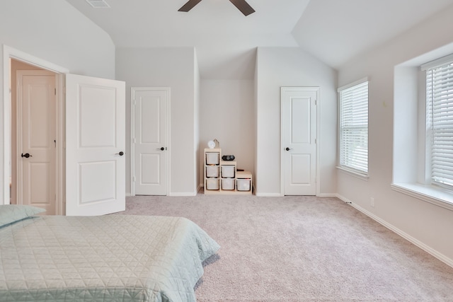 carpeted bedroom with multiple windows, ceiling fan, and vaulted ceiling