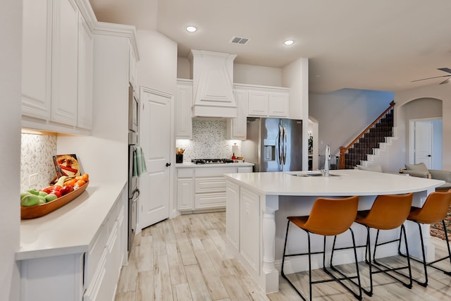 kitchen featuring a sink, stainless steel appliances, custom exhaust hood, and a kitchen breakfast bar