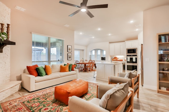 living room with ceiling fan, light wood-type flooring, and a fireplace