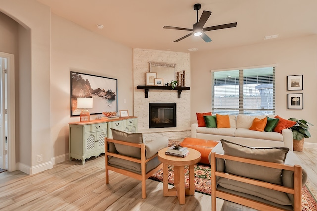 living room featuring ceiling fan, a fireplace, and light hardwood / wood-style flooring