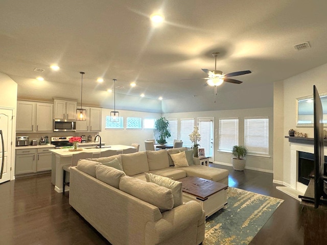 living room with dark wood-type flooring, ceiling fan, and vaulted ceiling