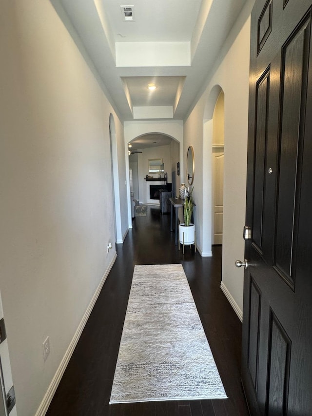 hallway featuring a raised ceiling and dark wood-type flooring