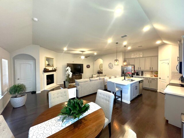 kitchen with vaulted ceiling, a kitchen island with sink, sink, pendant lighting, and white cabinetry