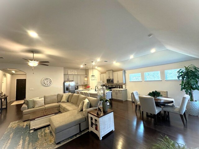 kitchen featuring dark wood-type flooring, a kitchen island with sink, vaulted ceiling, appliances with stainless steel finishes, and decorative light fixtures