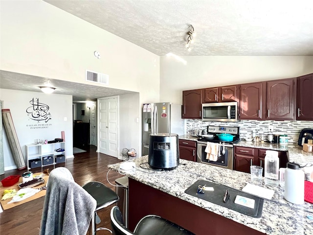 kitchen featuring light stone countertops, dark wood-type flooring, stainless steel appliances, and a textured ceiling