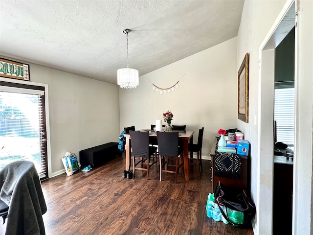 dining space featuring lofted ceiling, dark hardwood / wood-style flooring, a chandelier, and a textured ceiling