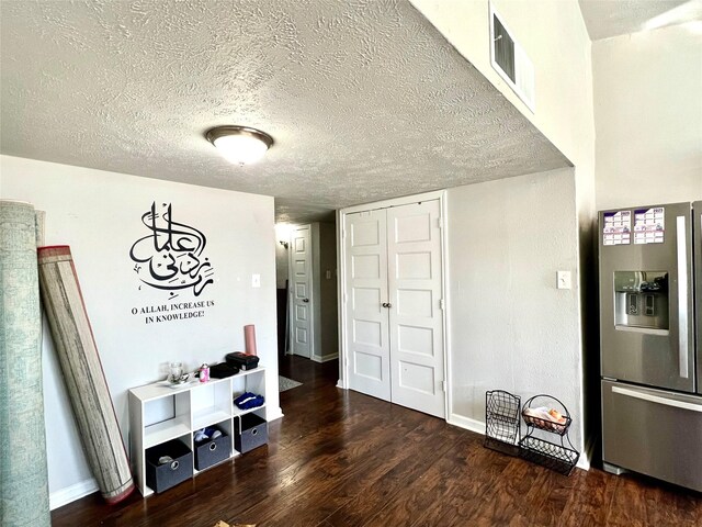 interior space featuring stainless steel fridge, dark wood-type flooring, and a textured ceiling