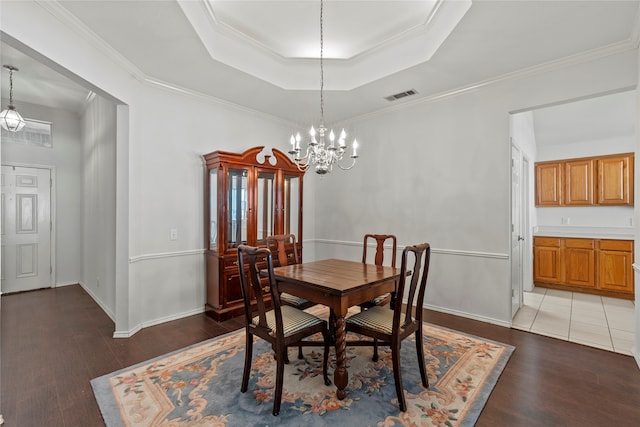 dining room with a notable chandelier, wood-type flooring, ornamental molding, and a tray ceiling