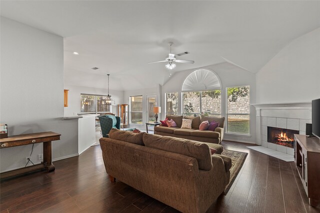 living room featuring dark hardwood / wood-style flooring, vaulted ceiling, ceiling fan, and a tiled fireplace