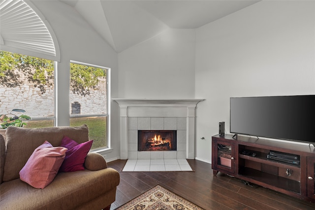 living room with hardwood / wood-style floors, lofted ceiling, and a tiled fireplace