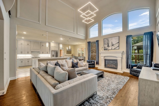 living room with a notable chandelier, a towering ceiling, and wood-type flooring