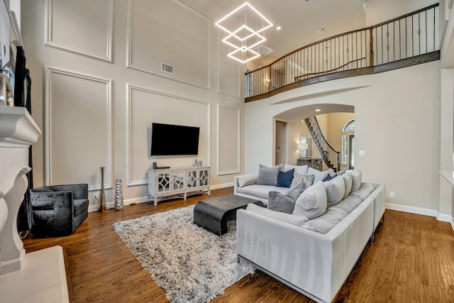 living room with a high ceiling, a notable chandelier, and dark hardwood / wood-style flooring