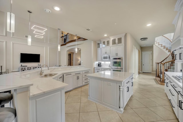 kitchen with light stone counters, hanging light fixtures, white cabinets, and a kitchen island