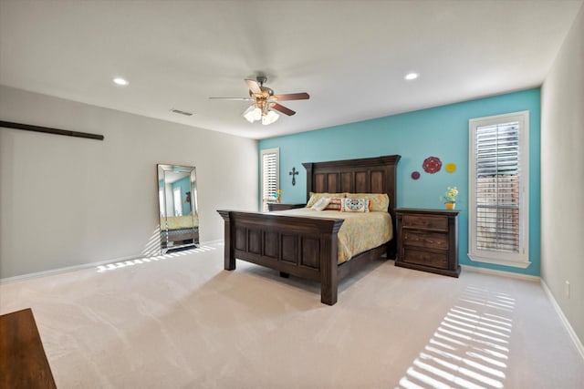 bedroom with ceiling fan, multiple windows, and light colored carpet