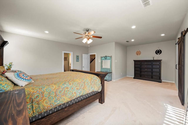 bedroom featuring ceiling fan, a barn door, and light colored carpet