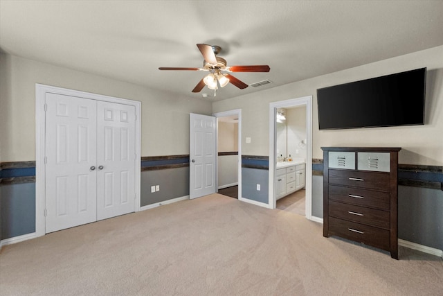 unfurnished bedroom with light carpet, a closet, ceiling fan, and connected bathroom