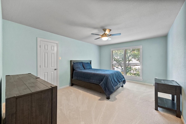 carpeted bedroom featuring ceiling fan and a textured ceiling