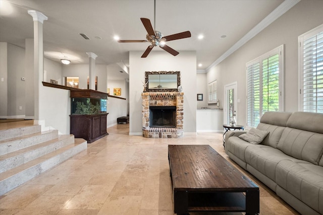 living room with a fireplace, ornamental molding, ornate columns, and ceiling fan