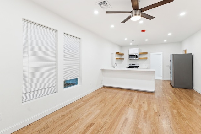 kitchen featuring white cabinets, ceiling fan, light wood-type flooring, kitchen peninsula, and stainless steel appliances