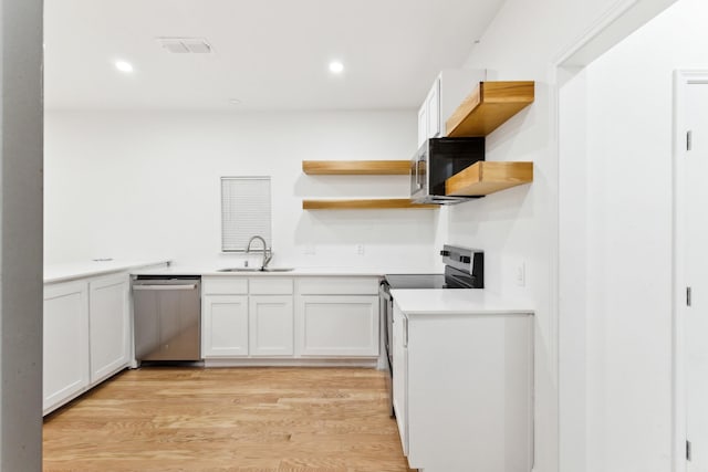 kitchen featuring light wood-type flooring, range with electric cooktop, stainless steel dishwasher, sink, and white cabinetry