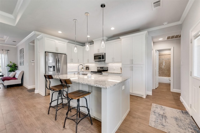 kitchen featuring a kitchen island with sink, white cabinets, sink, light stone counters, and stainless steel appliances