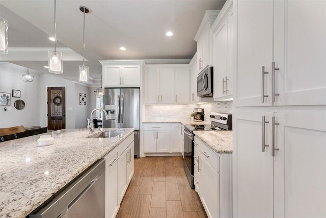 kitchen with pendant lighting, light stone countertops, white cabinetry, and stainless steel appliances