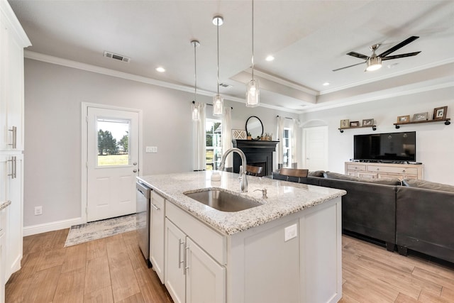 kitchen featuring light stone countertops, a kitchen island with sink, sink, decorative light fixtures, and white cabinets