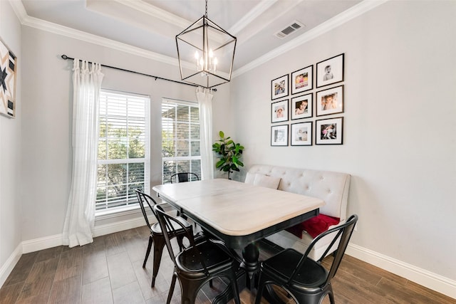 dining space featuring breakfast area, ornamental molding, a raised ceiling, dark wood-type flooring, and a chandelier