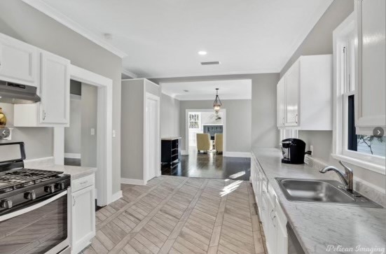 kitchen featuring white cabinetry, stainless steel range with gas cooktop, sink, and extractor fan