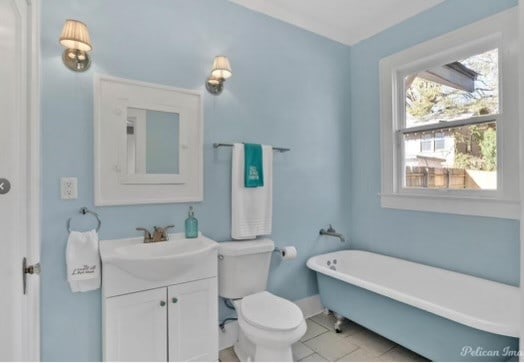 bathroom featuring a bathing tub, vanity, toilet, and tile patterned floors