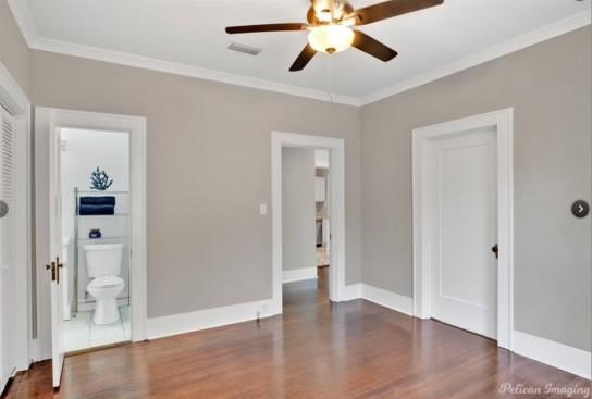 unfurnished bedroom featuring dark hardwood / wood-style floors, ceiling fan, crown molding, and ensuite bath