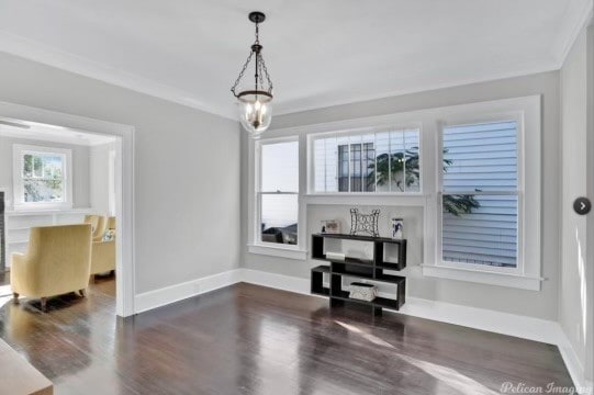 misc room with ornamental molding, dark wood-type flooring, and a notable chandelier