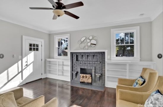 living room with dark hardwood / wood-style floors, ceiling fan, ornamental molding, and a fireplace