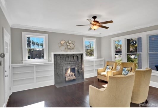 living room featuring ceiling fan, ornamental molding, dark hardwood / wood-style floors, and a brick fireplace