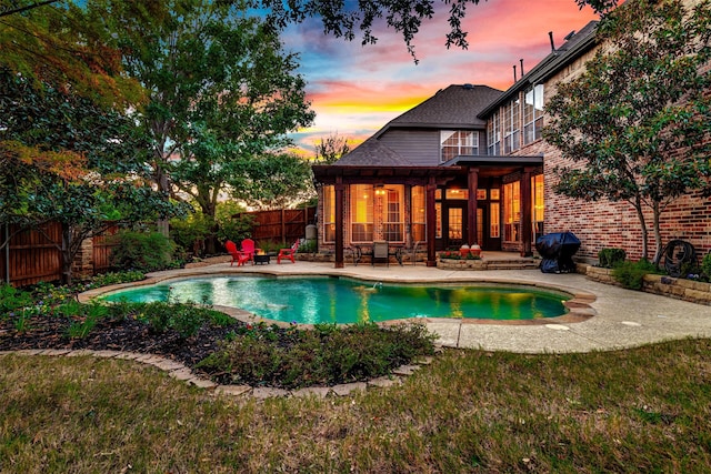 pool at dusk with area for grilling and a patio area